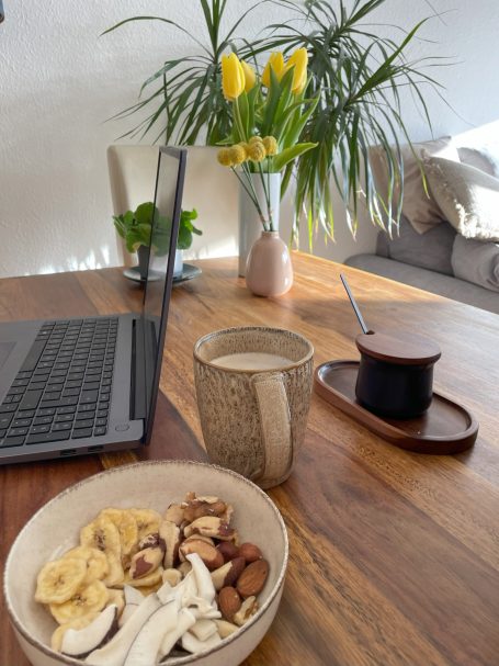 Frühstückstisch mit einer Schüssel Nüssen, Kaffee und einer Vase mit gelben Tulpen.